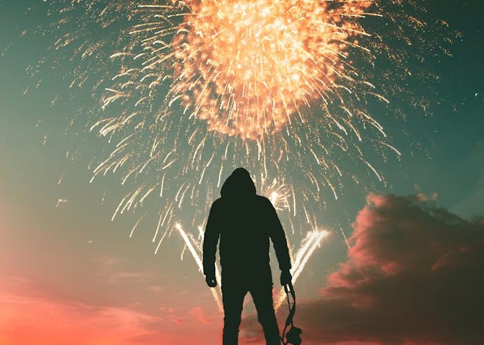 Silhouette Photo of Standing Man Holding Camera Looking at Fireworks Display